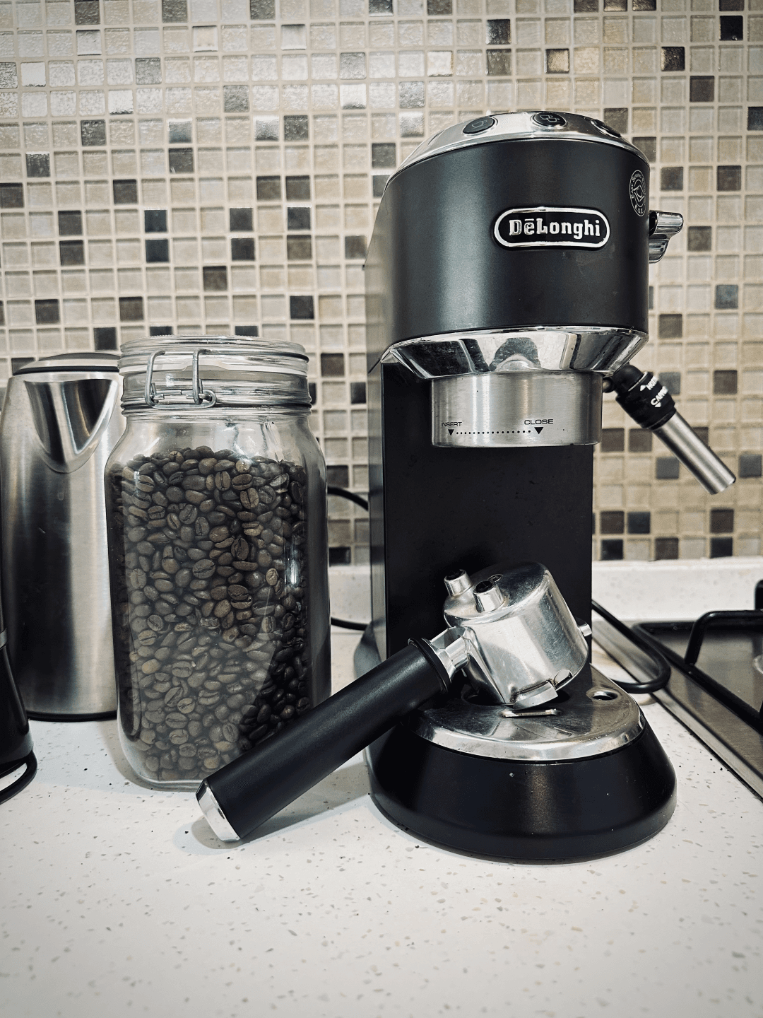 A photograph of an espresso machine next to a jar filled with coffee beans at the common kitchen of InterCube hostel in Dubai