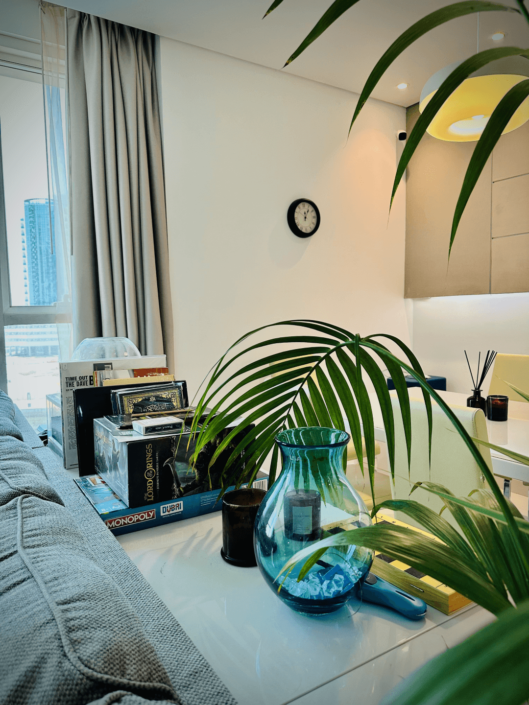 A photograph of a cozy living space at InterCube hostel in Dubai, featuring a table with a green vase, candles, books, and board games