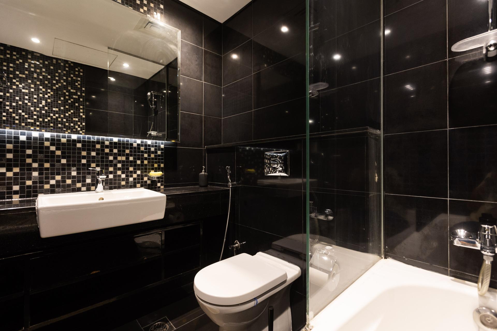 Photograph of a stylish bathroom at InterCube hostel in Dubai, featuring a modern sink, toilet, and a black and white tiled wall