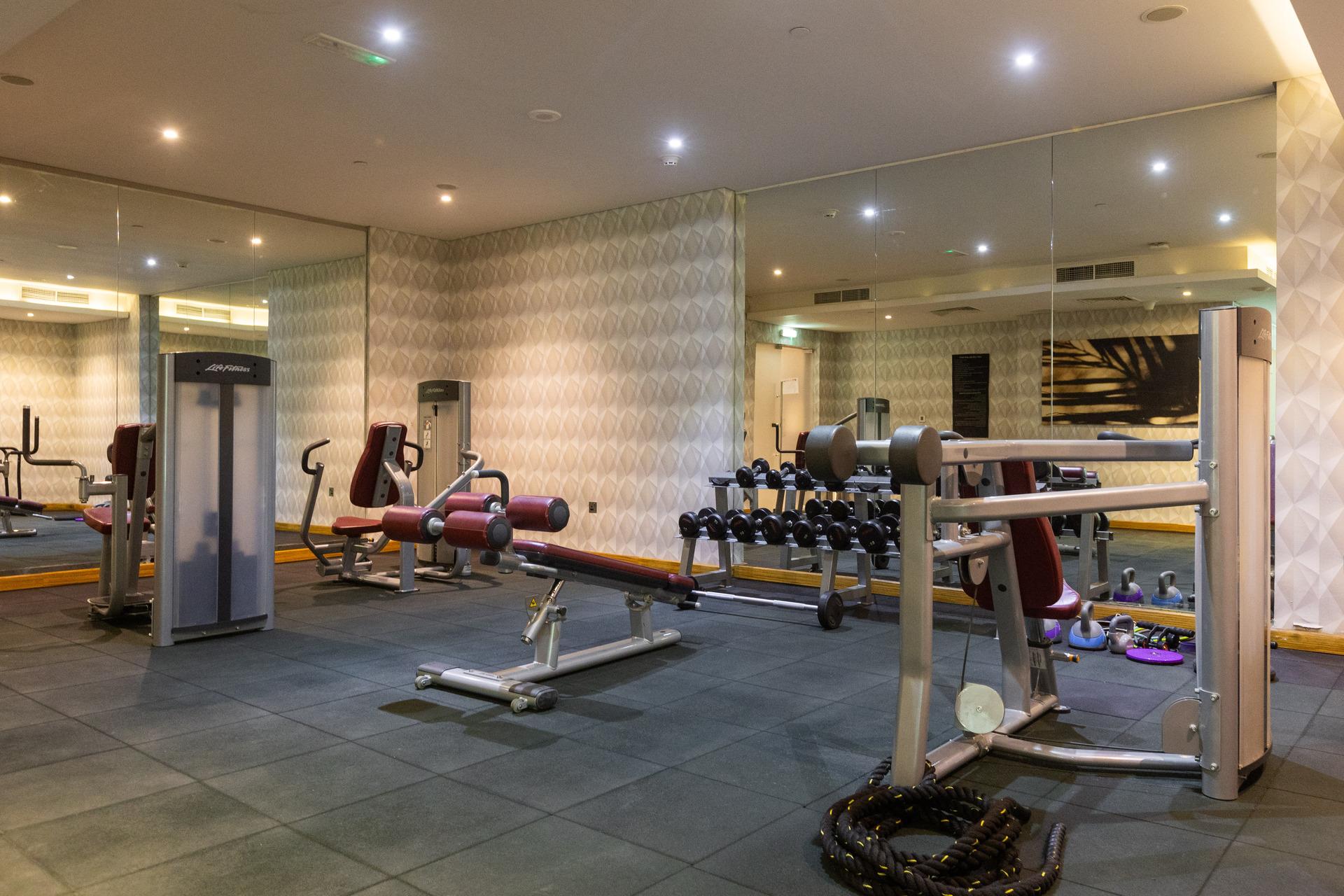 Photograph of the fitness center at InterCube hostel in Dubai, equipped with various exercise machines and free weights