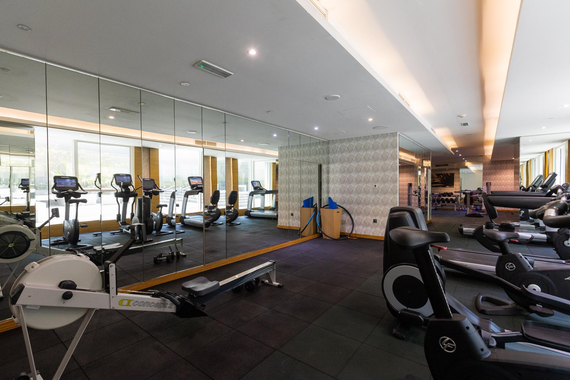 Photograph of a gym with exercise machines and a mirrored wall at InterCube hostel in Dubai